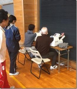 2人ずつ椅子に座り、血圧測定している様子の写真